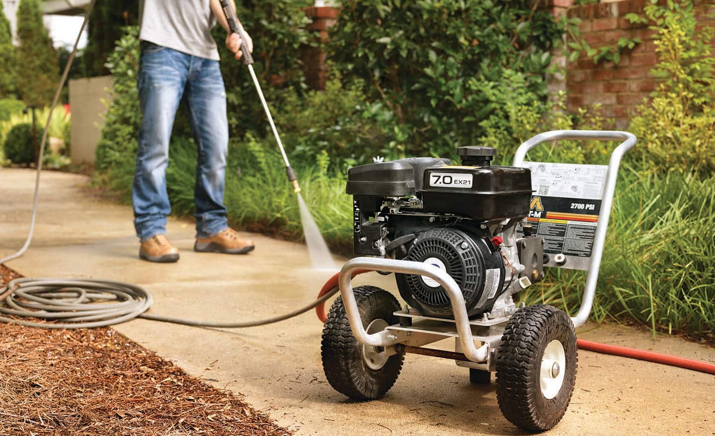 A man pressure washing a sidewalk. 