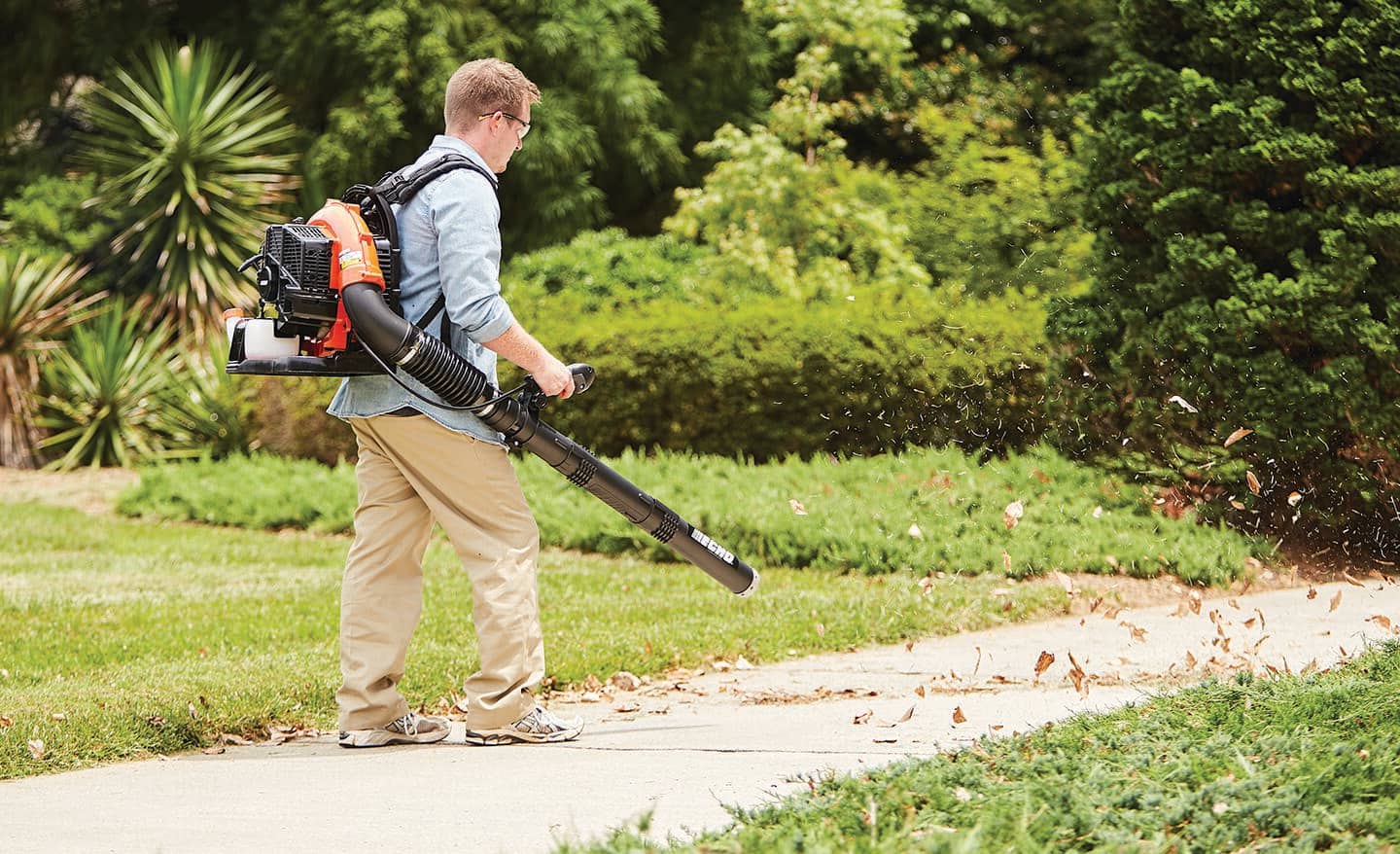 A person uses a backpack-style leaf blower.