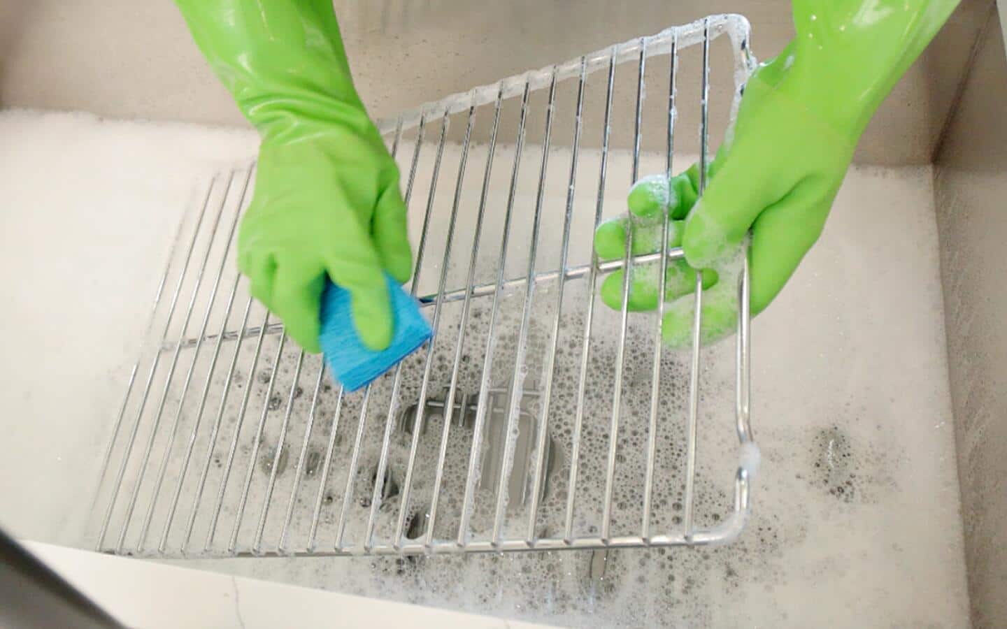Someone cleaning oven racks in a sink. Someone cleaning oven racks in a sink.