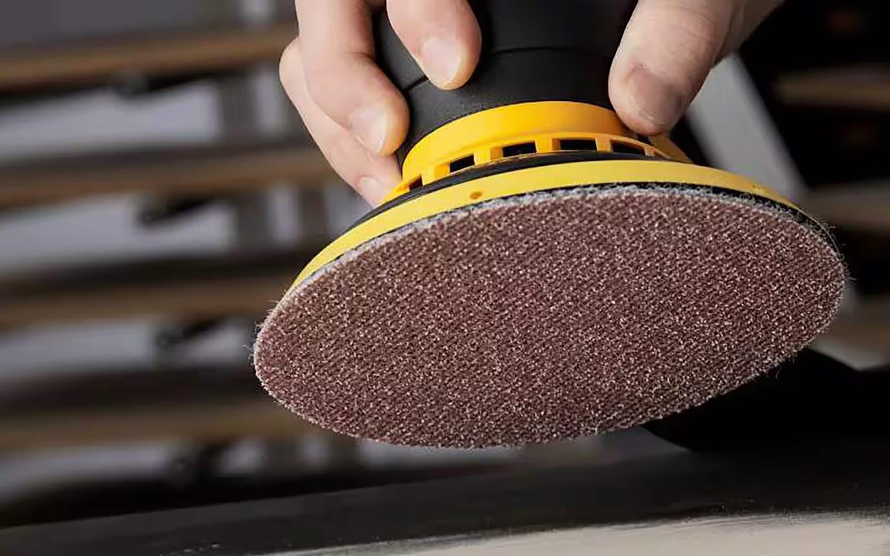 An orbital sander installed with a ceramic sandpaper disc.