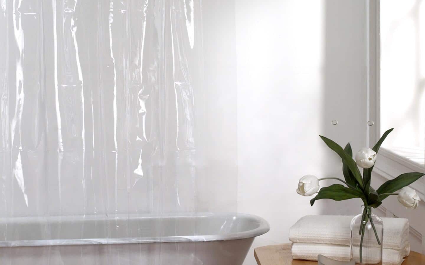 A clear shower curtain liner inside a shower stall.