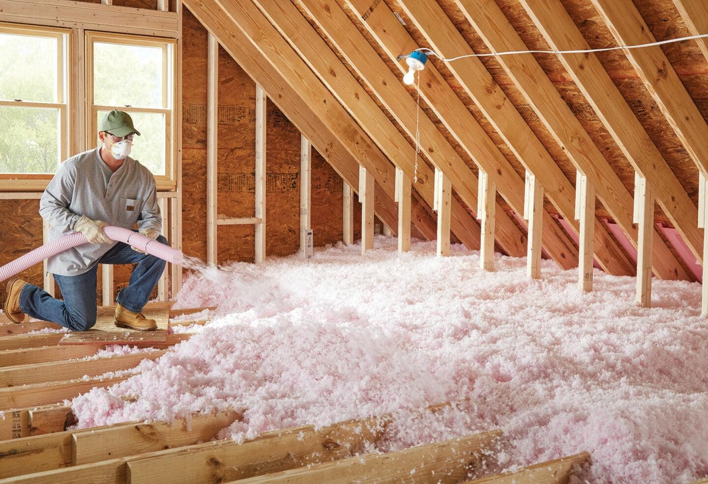 Professional installing blown-in insulation in an attic space. 