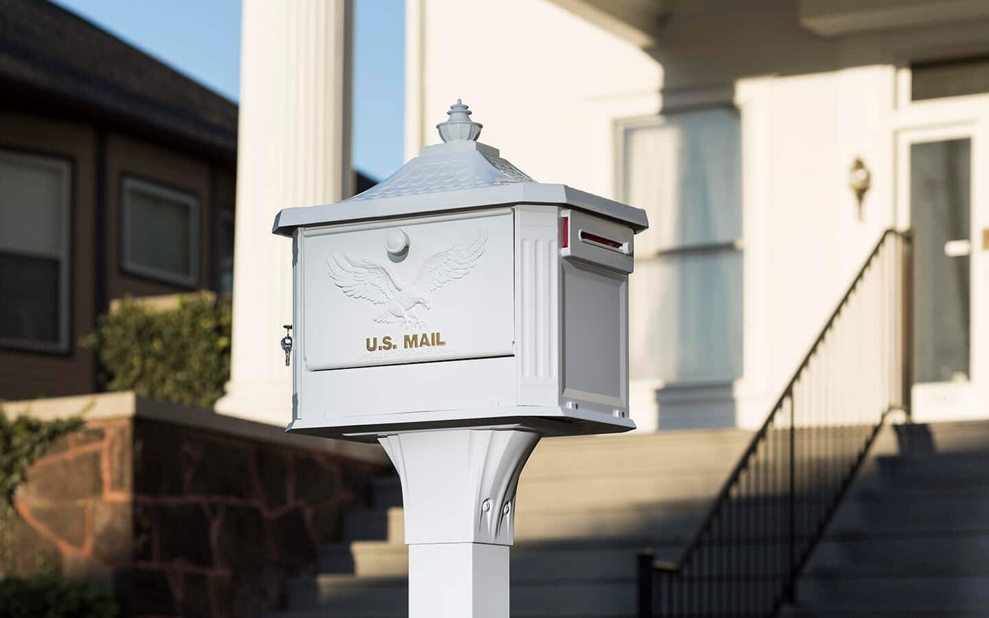 A white mailbox placed in front of a white house. A white mailbox placed in front of a white house.