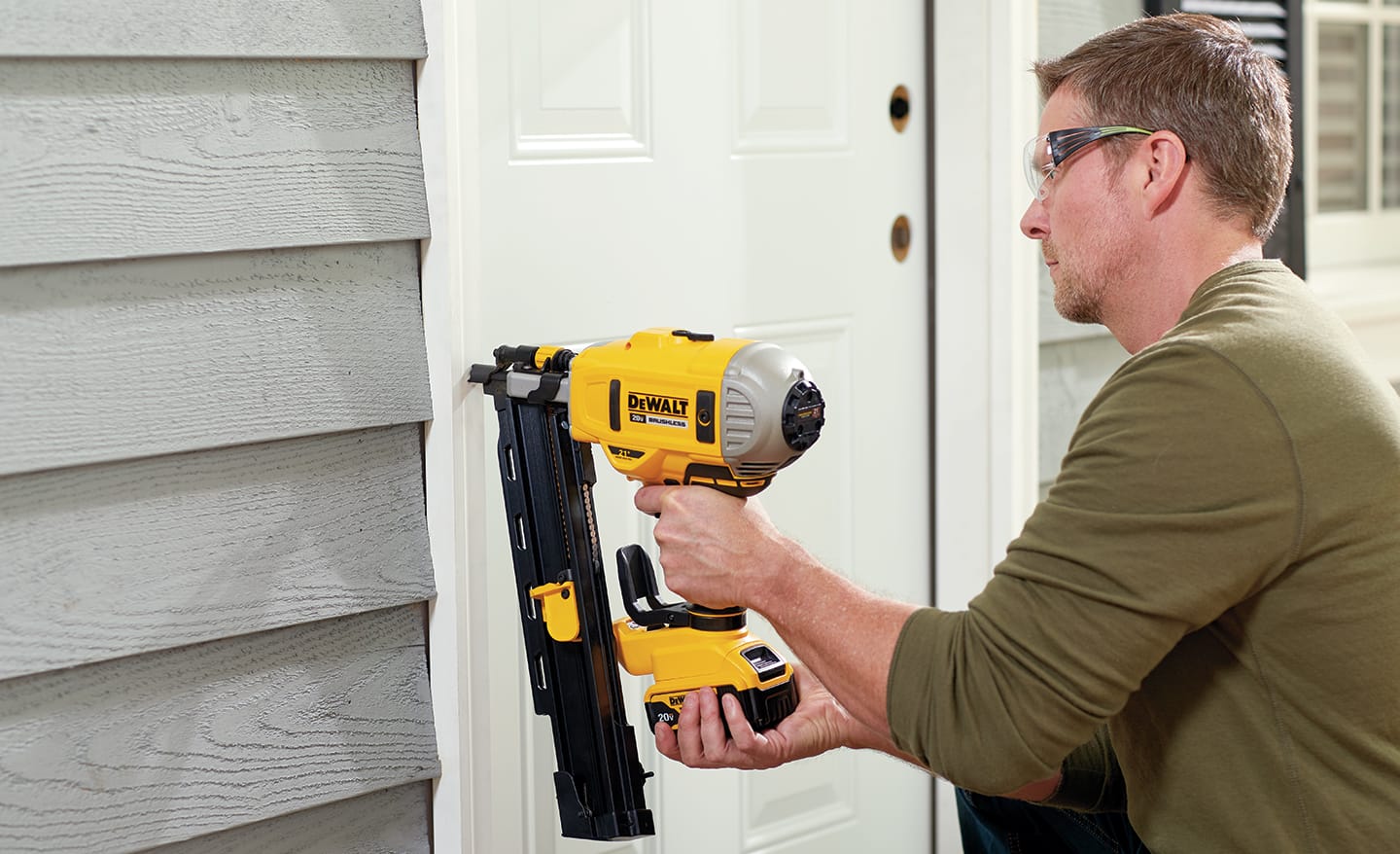 A man securing a new entry door outside the home.