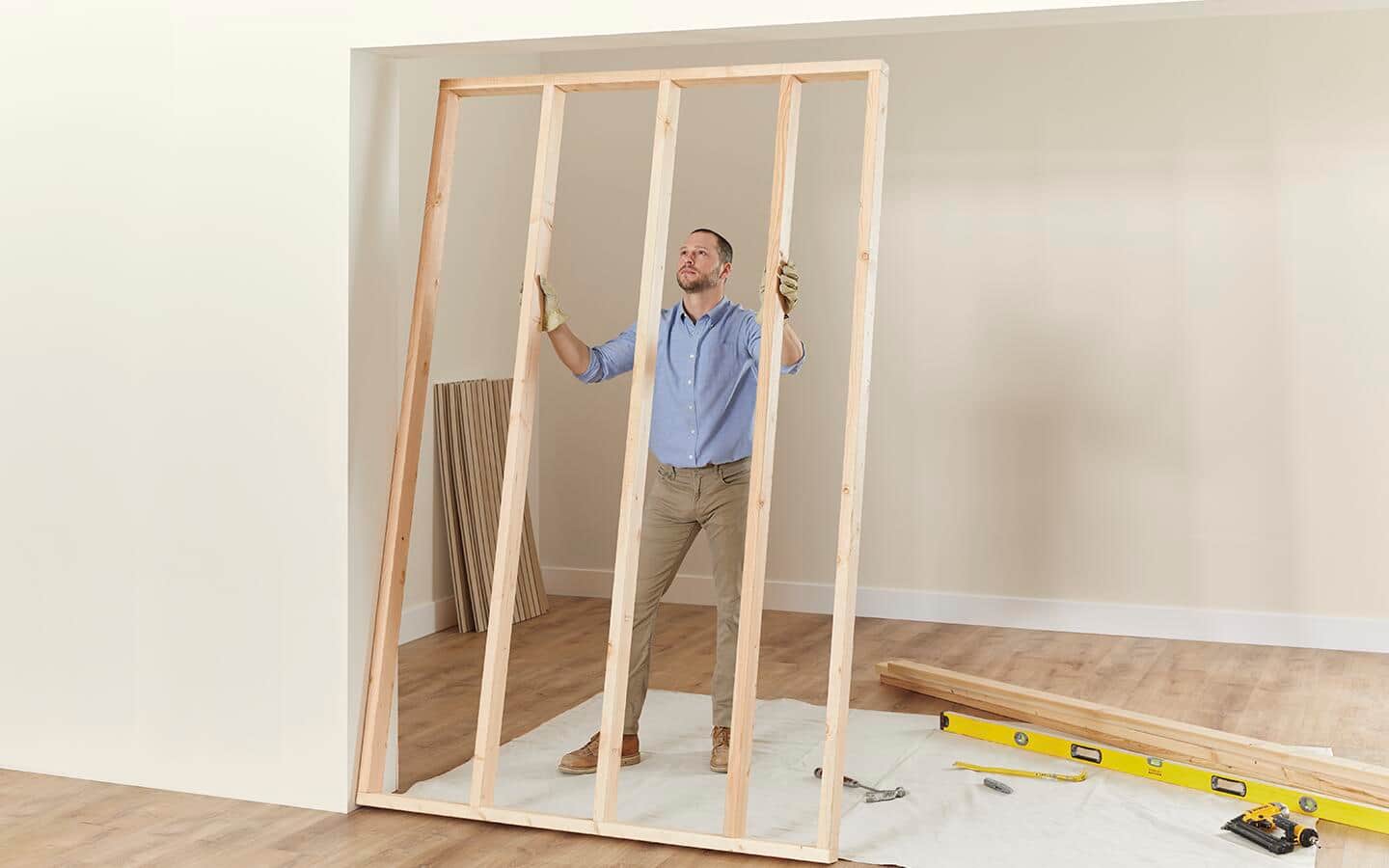 A man supporting a wood frame for a room divider.