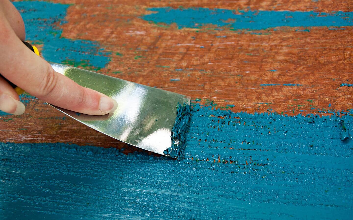 Someone stripping blue paint from a wood surface.