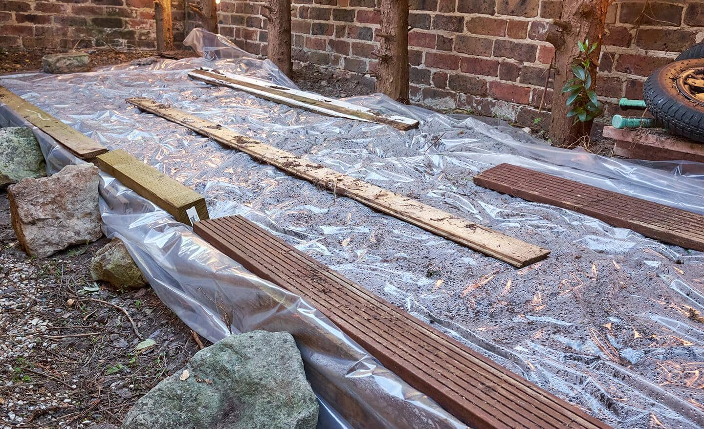 Garden bed covered with plastic and weighted down with lumber