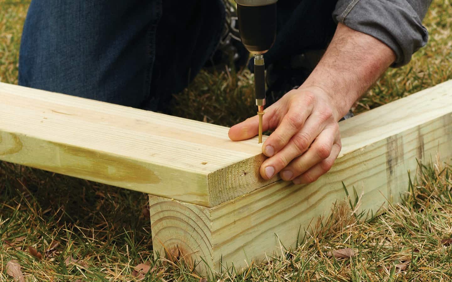 A person drills together two pieces of lumber for an enclosure's side wall frame. A person drills together two pieces of lumber for an enclosure's side wall frame.