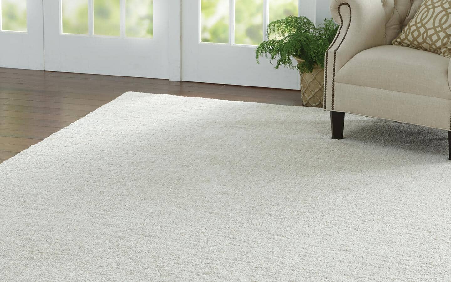 A solid rug lays under an arm chair in a monochromatic gray living room.