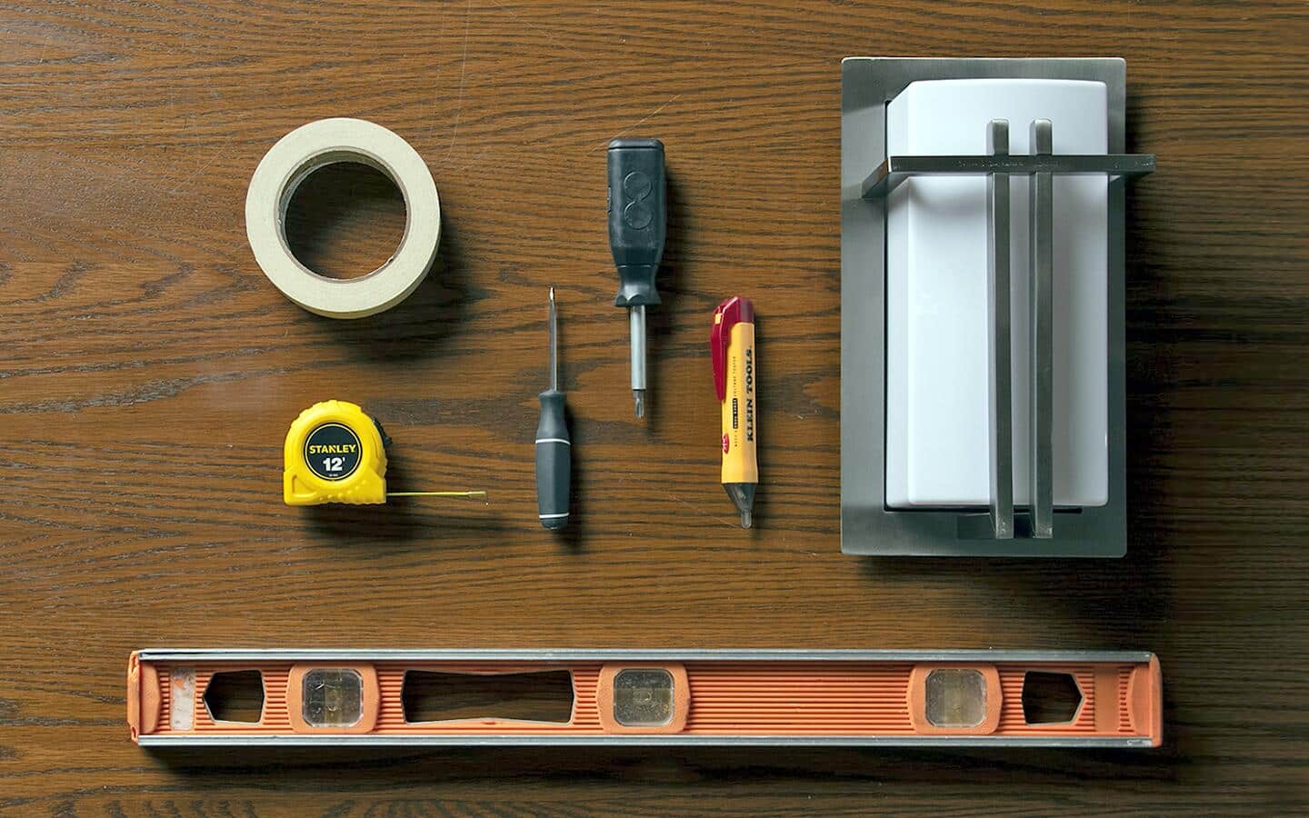 A tape measure, level and other tools laid out on a table. A tape measure, level and other tools laid out on a table.