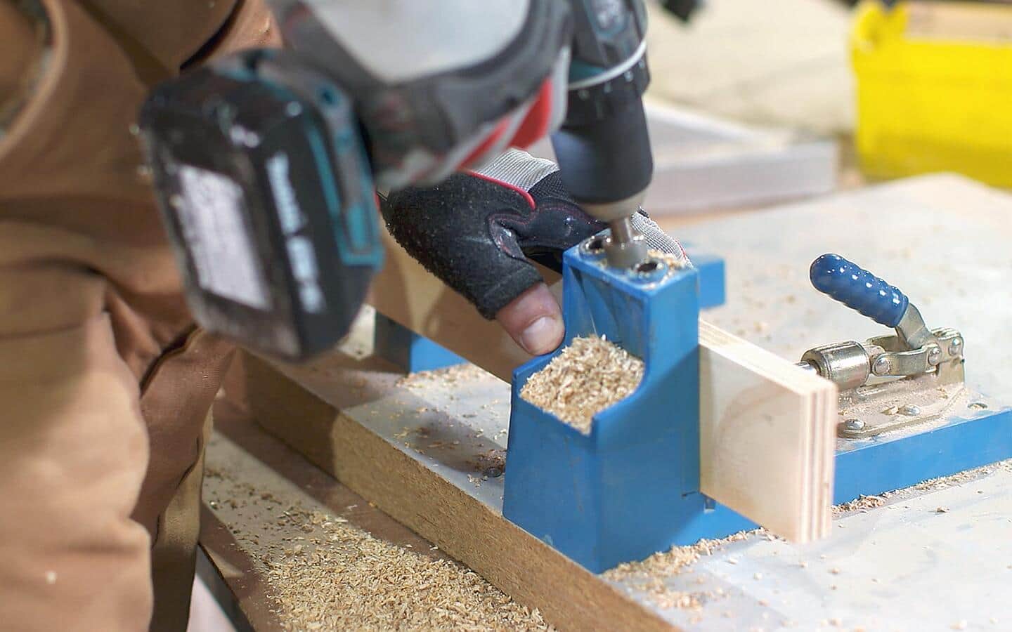 A drill is used to make pocket holes in plywood for a DIY desk project.