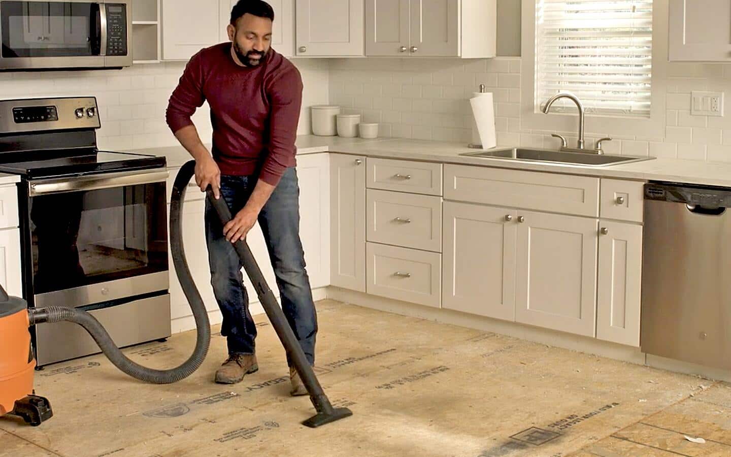 A person vacuuming a subfloor after removing vinyl flooring. A person vacuuming a subfloor after removing vinyl flooring.