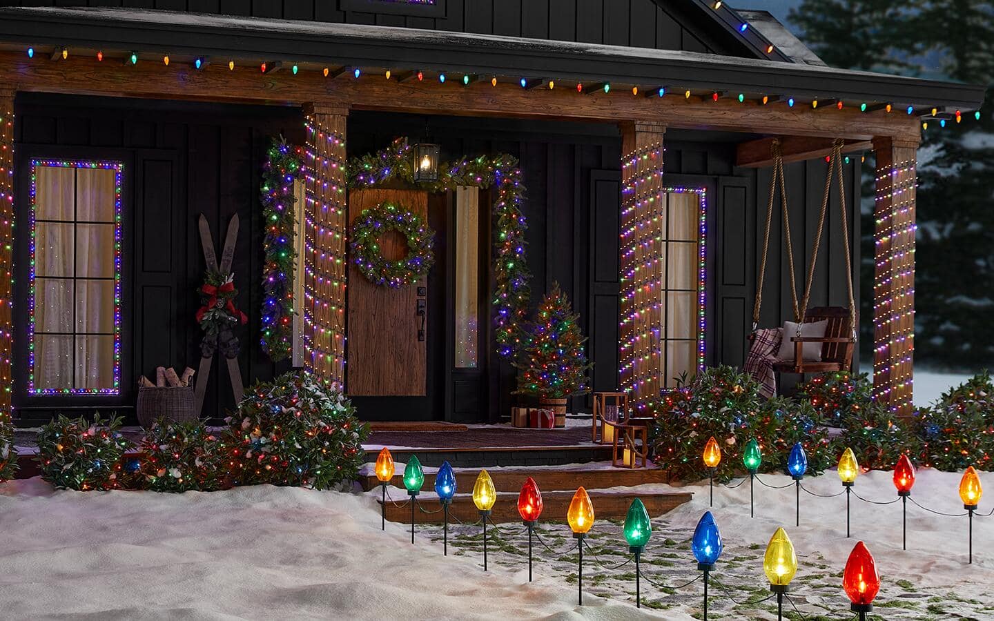 A pathway lined with holiday lights leads up to a front porch decorated with colorful string lights. A pathway lined with holiday lights leads up to a front porch decorated with colorful string lights.