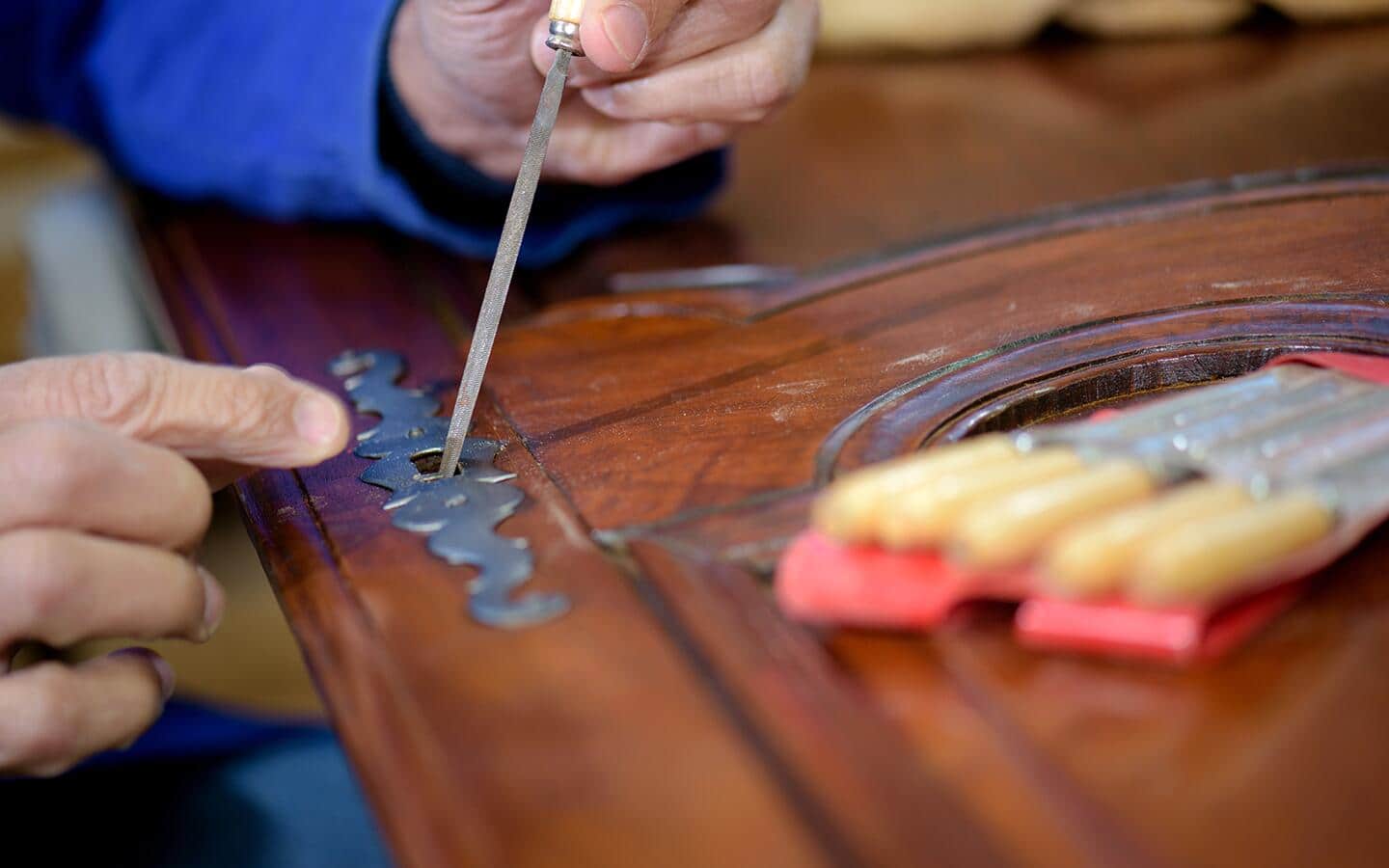 Someone removes a metal piece from a wood cabinet door.