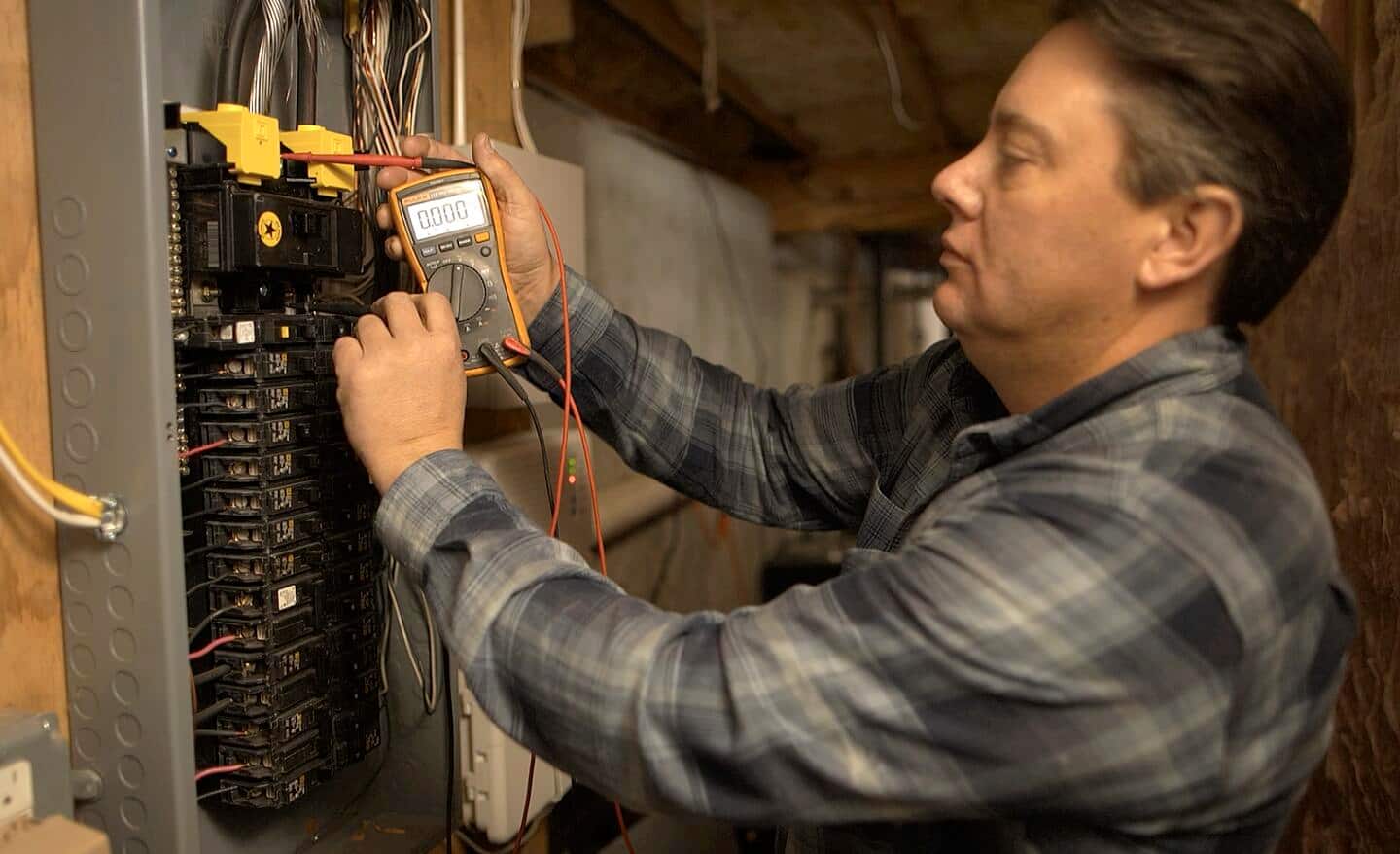 A person tests the voltage of a circuit breaker with a multimeter.
