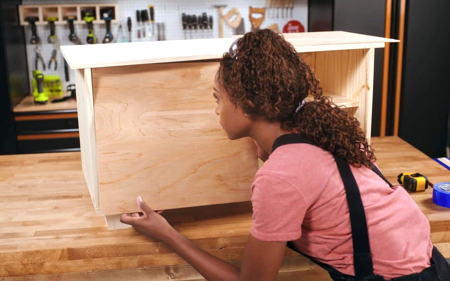 A person inserts a wooden board to serve as the rear door for a shoe rack. A person inserts a wooden board to serve as the rear door for a shoe rack.