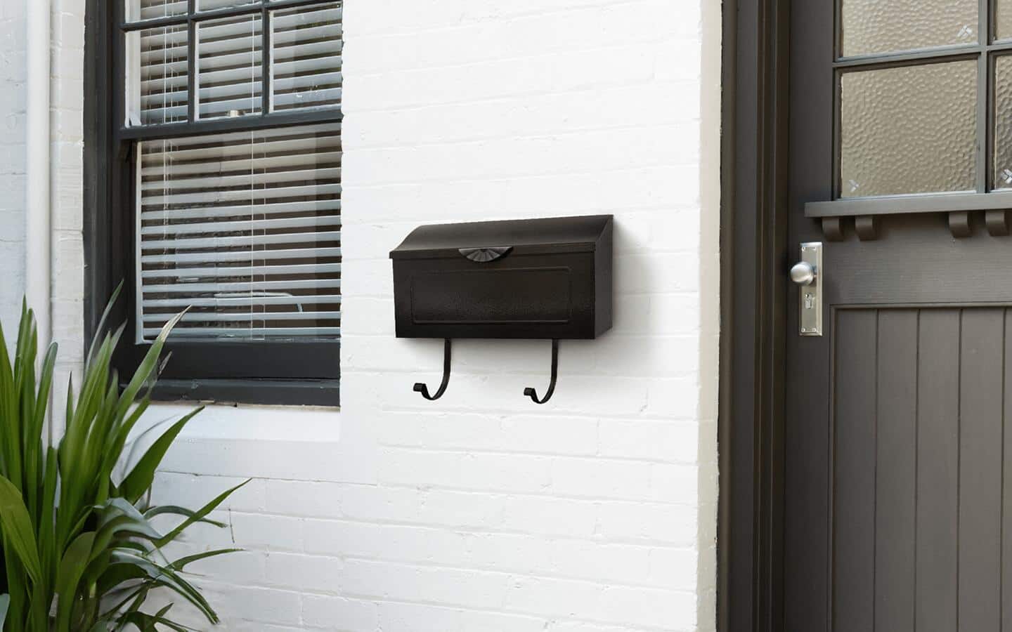 A black mailbox installed on a wall outside of a home. A black mailbox installed on a wall outside of a home.