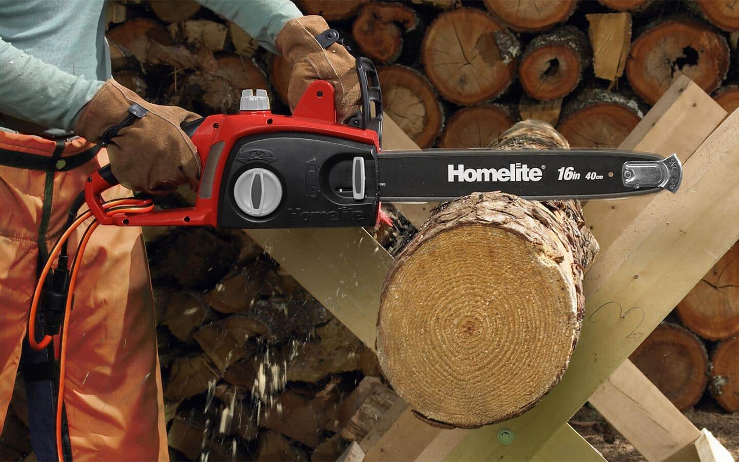 A gloved person using a red and black chainsaw to crosscut a log.