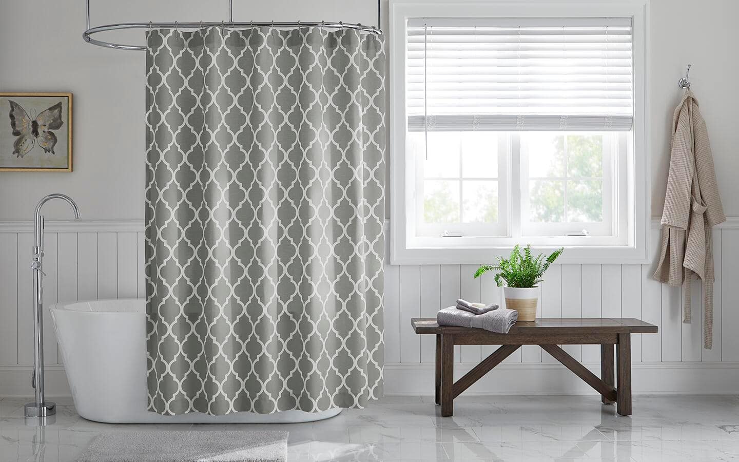 A gray and white-patterned shower curtain hanging in a marble bath.