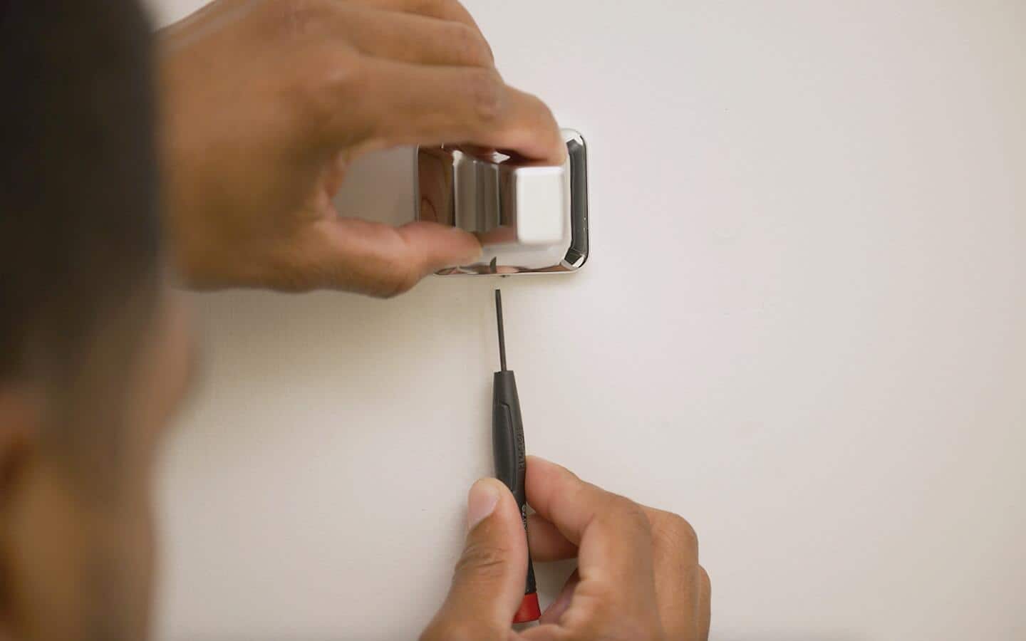 A person screwing a towel bar post to a bracket. A person screwing a towel bar post to a bracket.