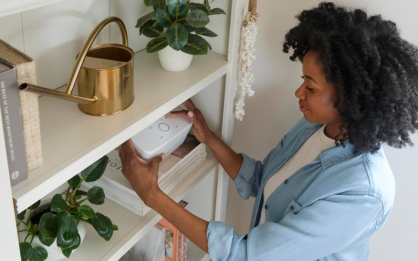 Woman placing a speaker on a book shelf. Woman placing a speaker on a book shelf.