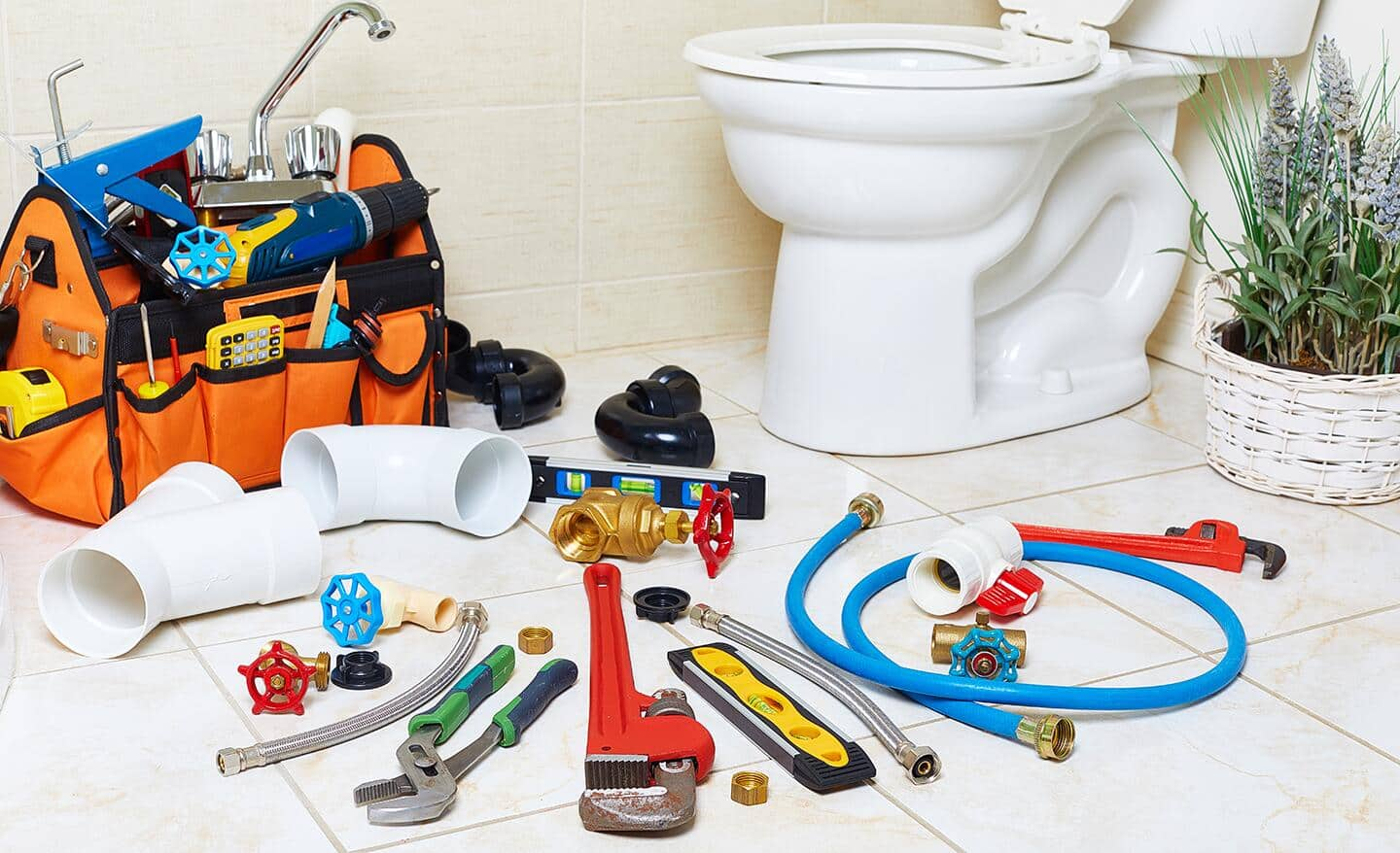 A variety of plumbing tools and supplies on a bathroom floor.