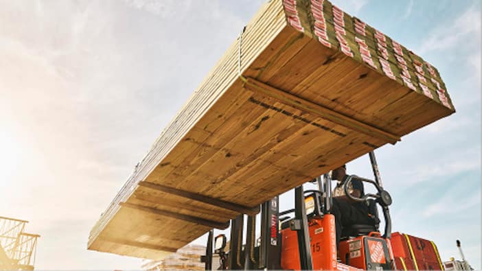 A forklift moves a stack of boards.