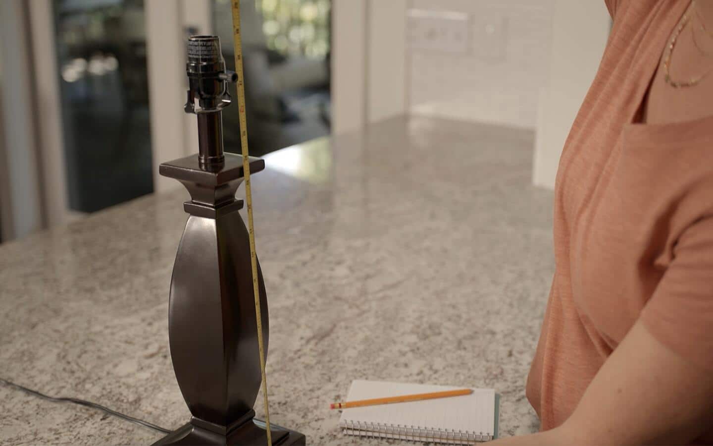 Someone measuring the height of a table lamp base. Someone measuring the height of a table lamp base.