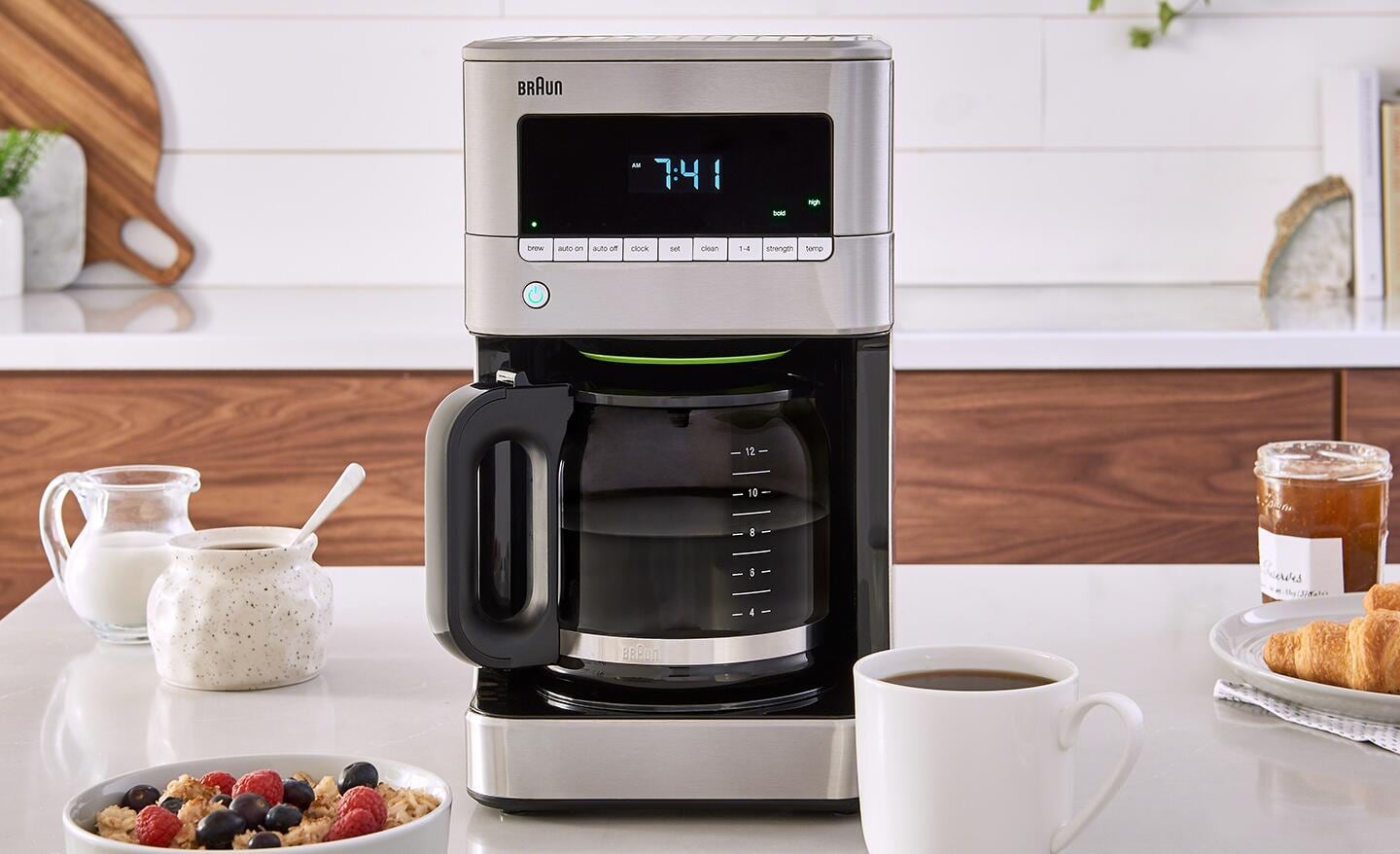 A drip coffee maker and cup, sugar and creamer on a countertop. A drip coffee maker and cup, sugar and creamer on a countertop.