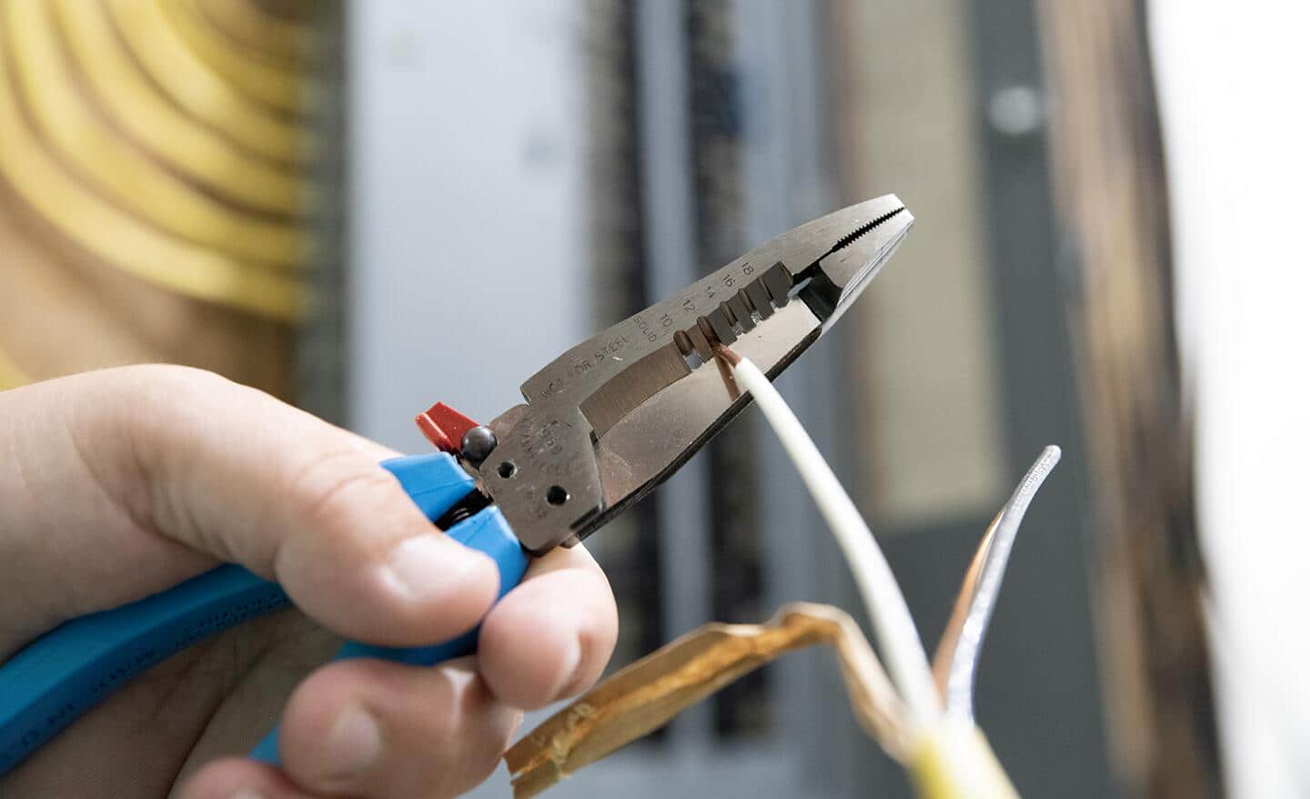 A person uses a pair of wire cutters to cut electrical wire.