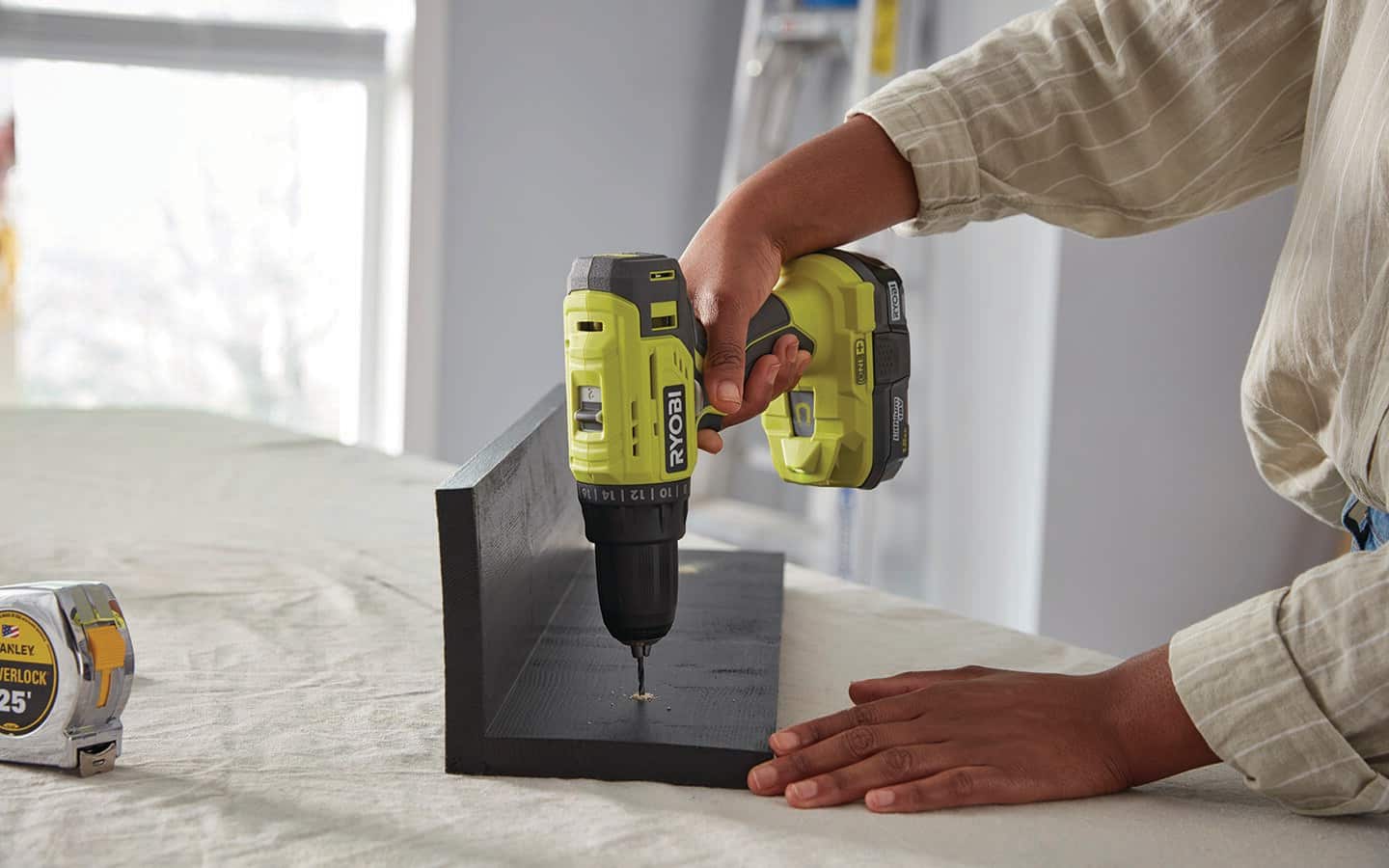 Someone works on a DIY coat hanger with a drill.