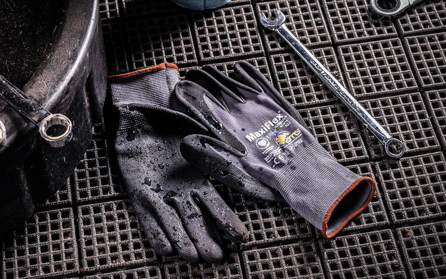 Work gloves and a wrench on a work surface.