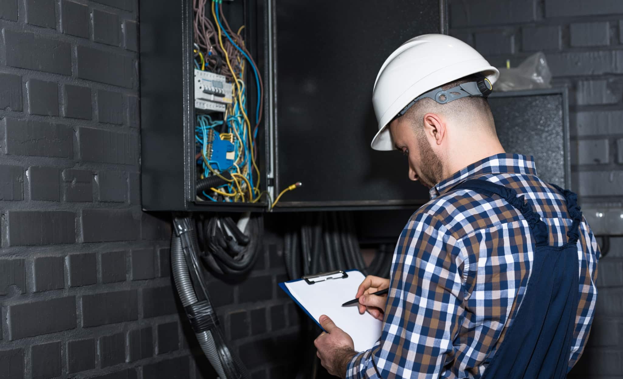 An electrician installs a breaker box.
