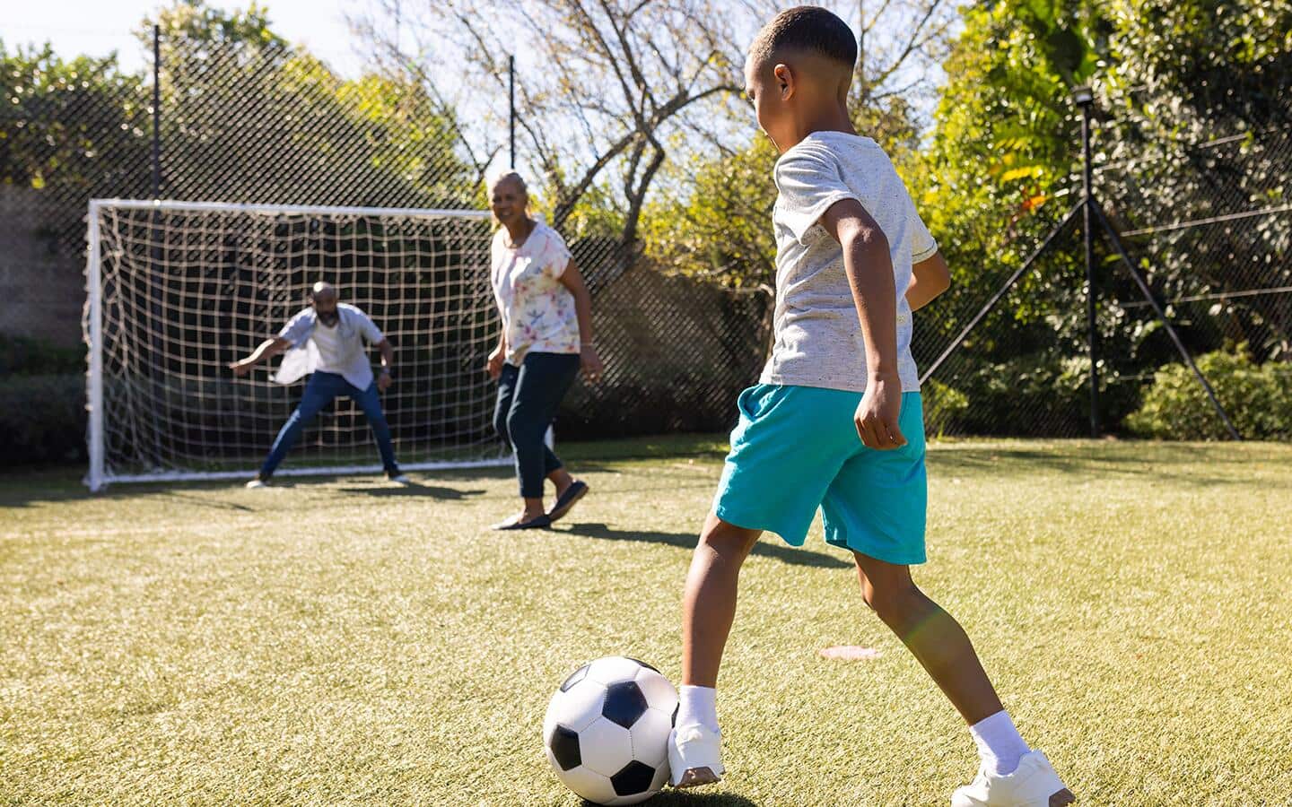 A kid playing soccer with parents in backyard. A kid playing soccer with parents in backyard.
