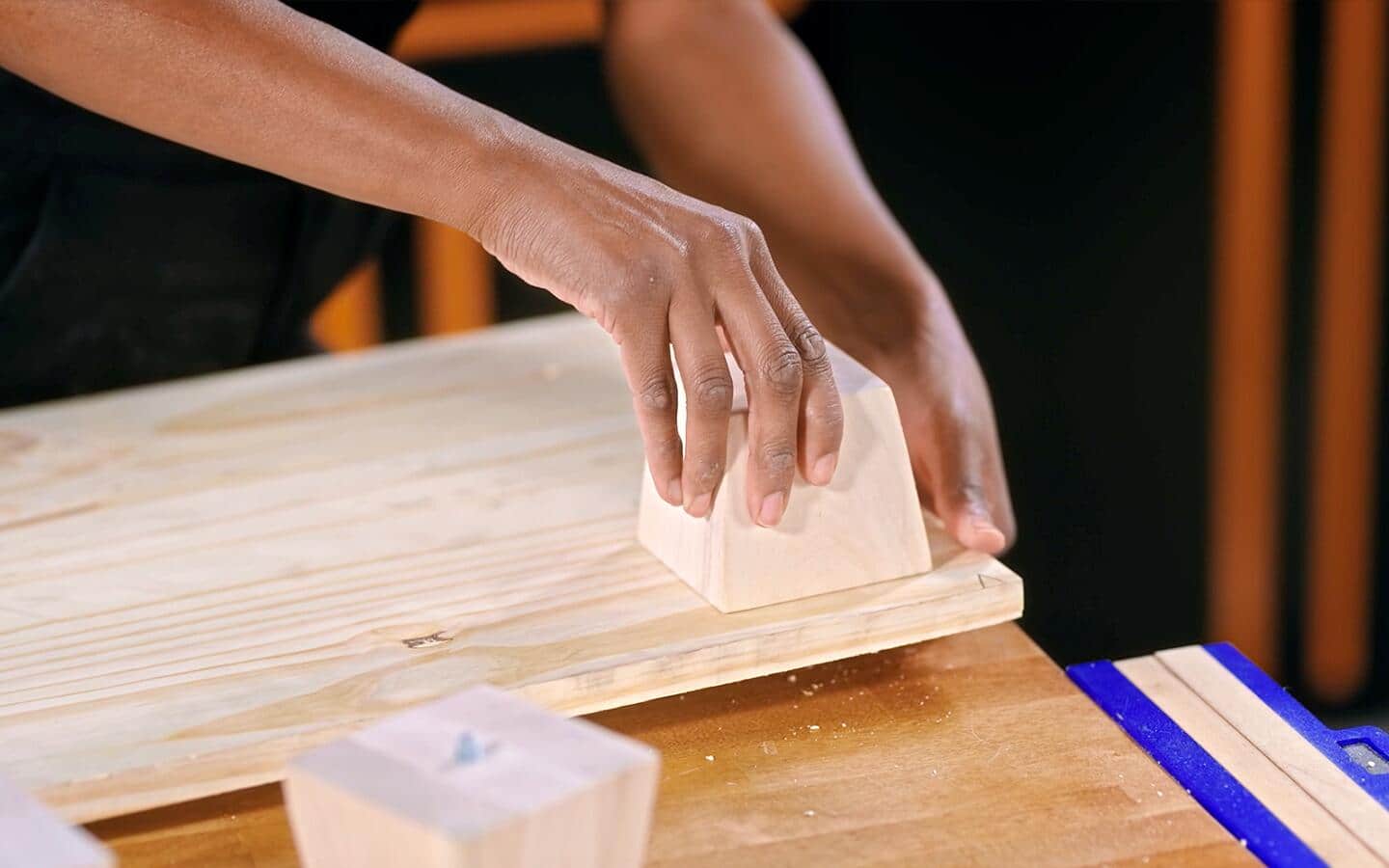 A wooden block being placed on a board to mark a shoe rack's foot placement. A wooden block being placed on a board to mark a shoe rack's foot placement.