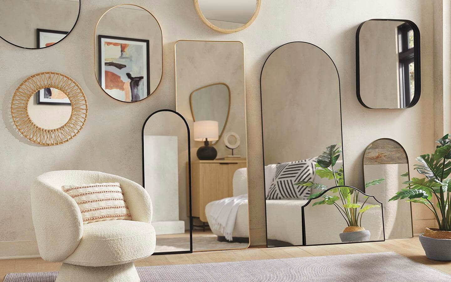 Mirrors of different sizes and shapes hanging on a beige living room wall.