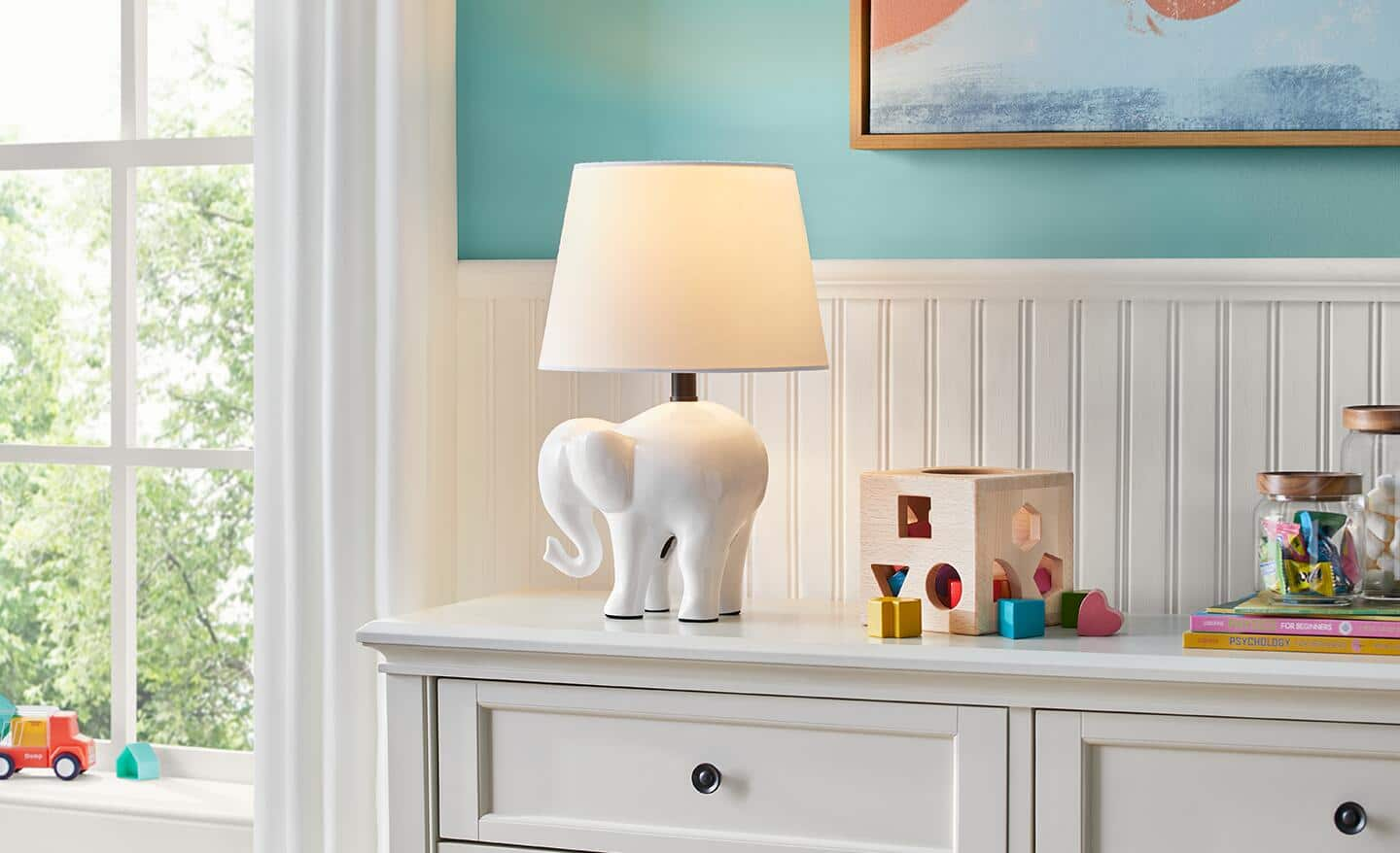 A white elephant lamp sits on a dresser. 