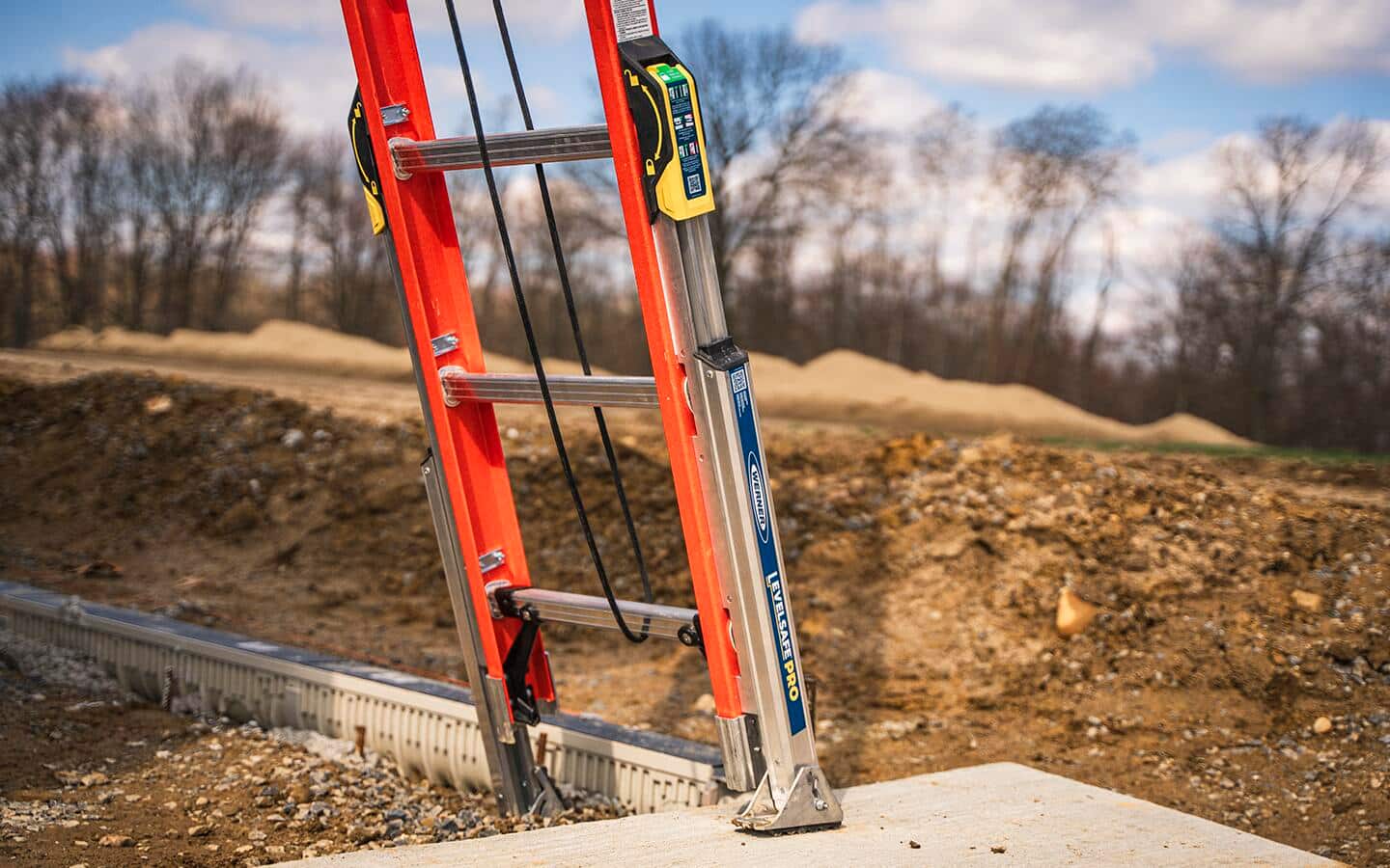 An orange ladder with an attached leveler for uneven surfaces.  