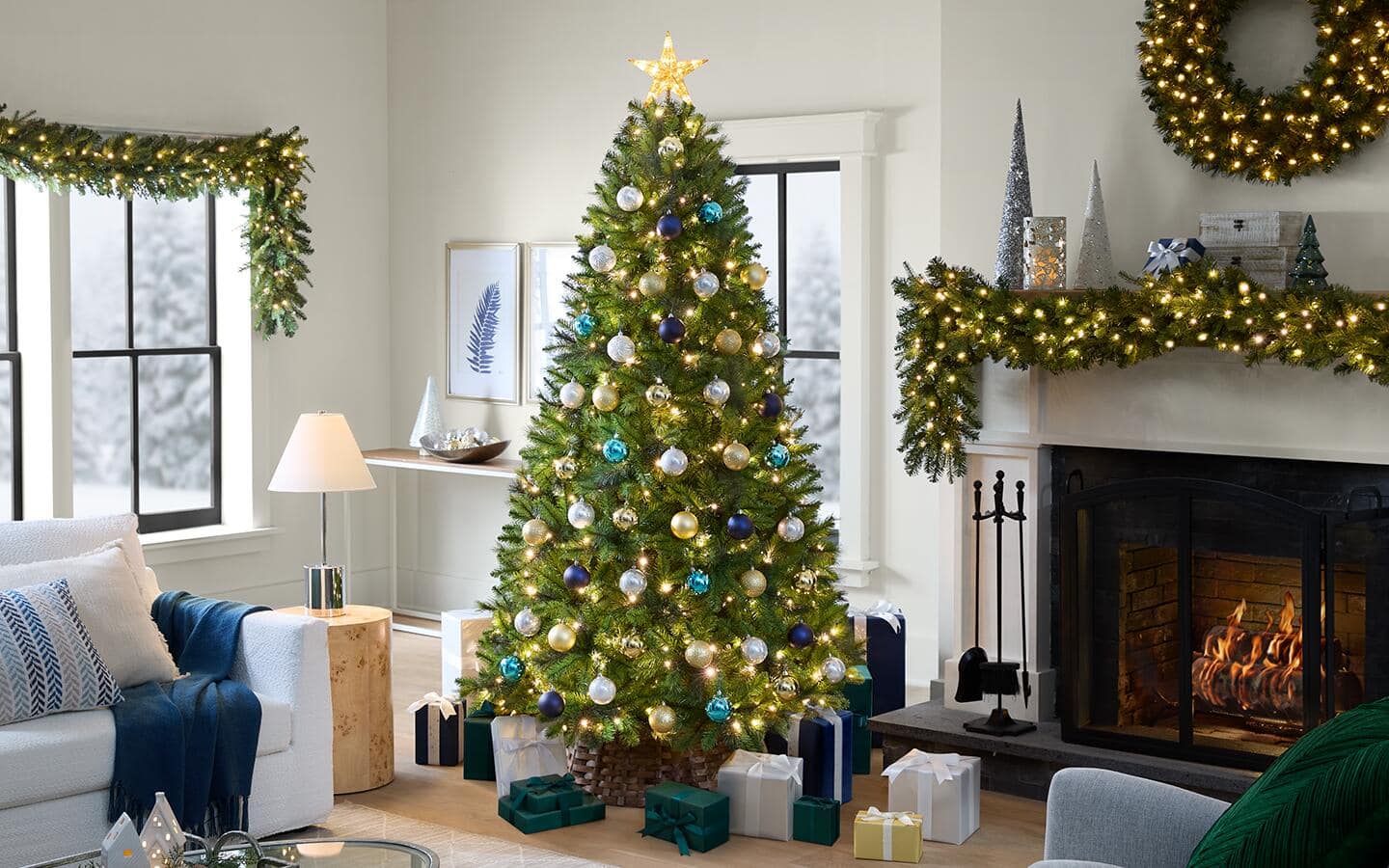 A living room featuring a blue and gold Christmas tree, wreath and window swag.