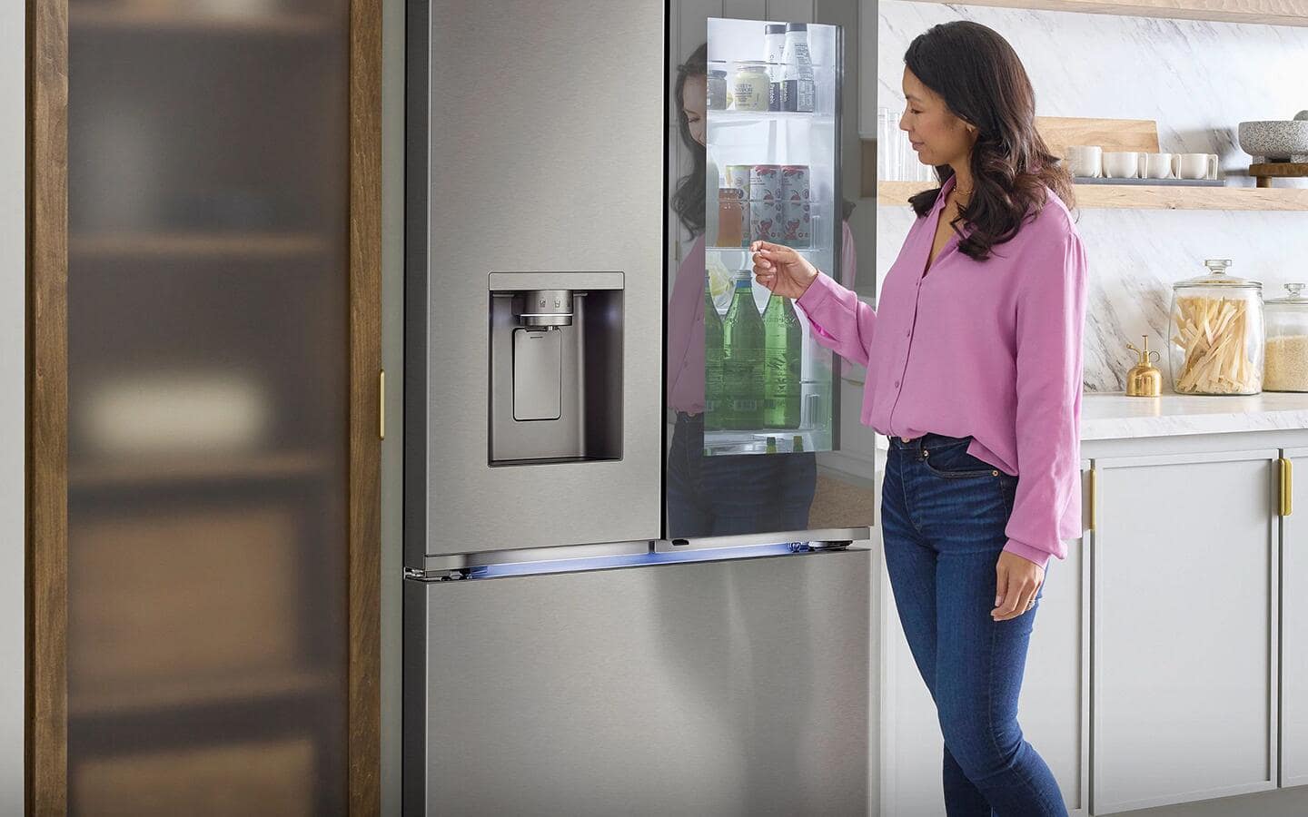 A person in a kitchen interacting with the door of a smart refrigerator.