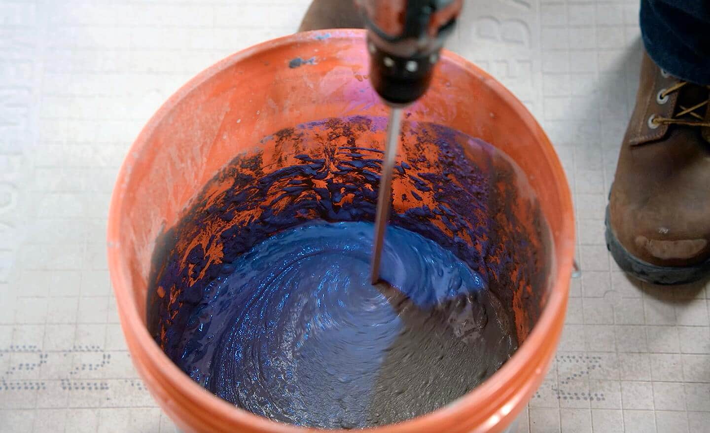 A person mixes grout mortar in a bucket.