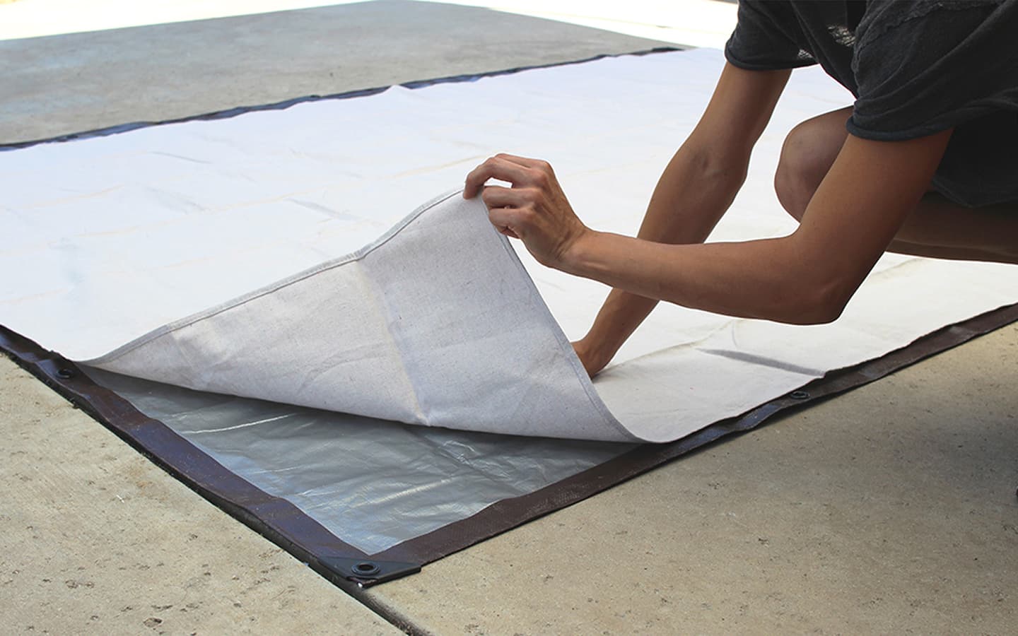 The drop cloth is unfolded on tp of the tarp.