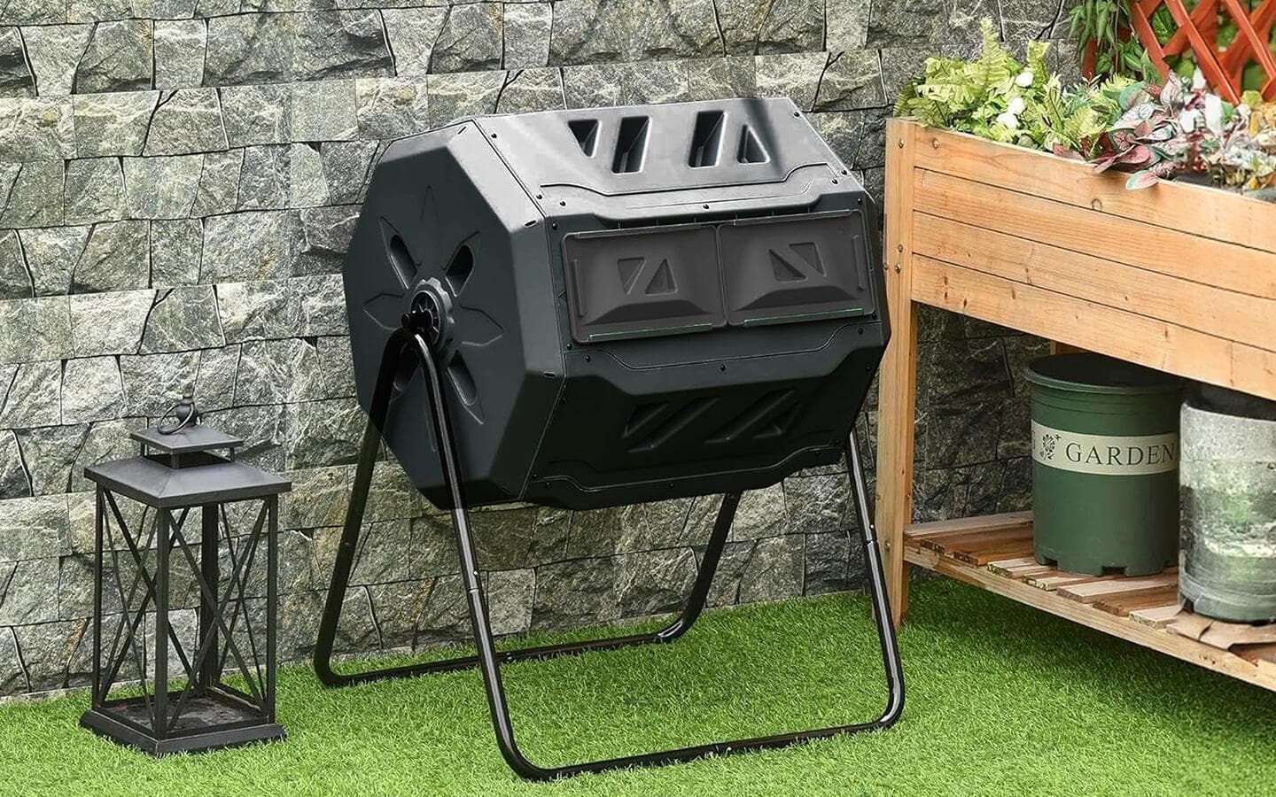 A tumbling composter sits on a patio next to a raised garden bed A tumbling composter sits on a patio next to a raised garden bed