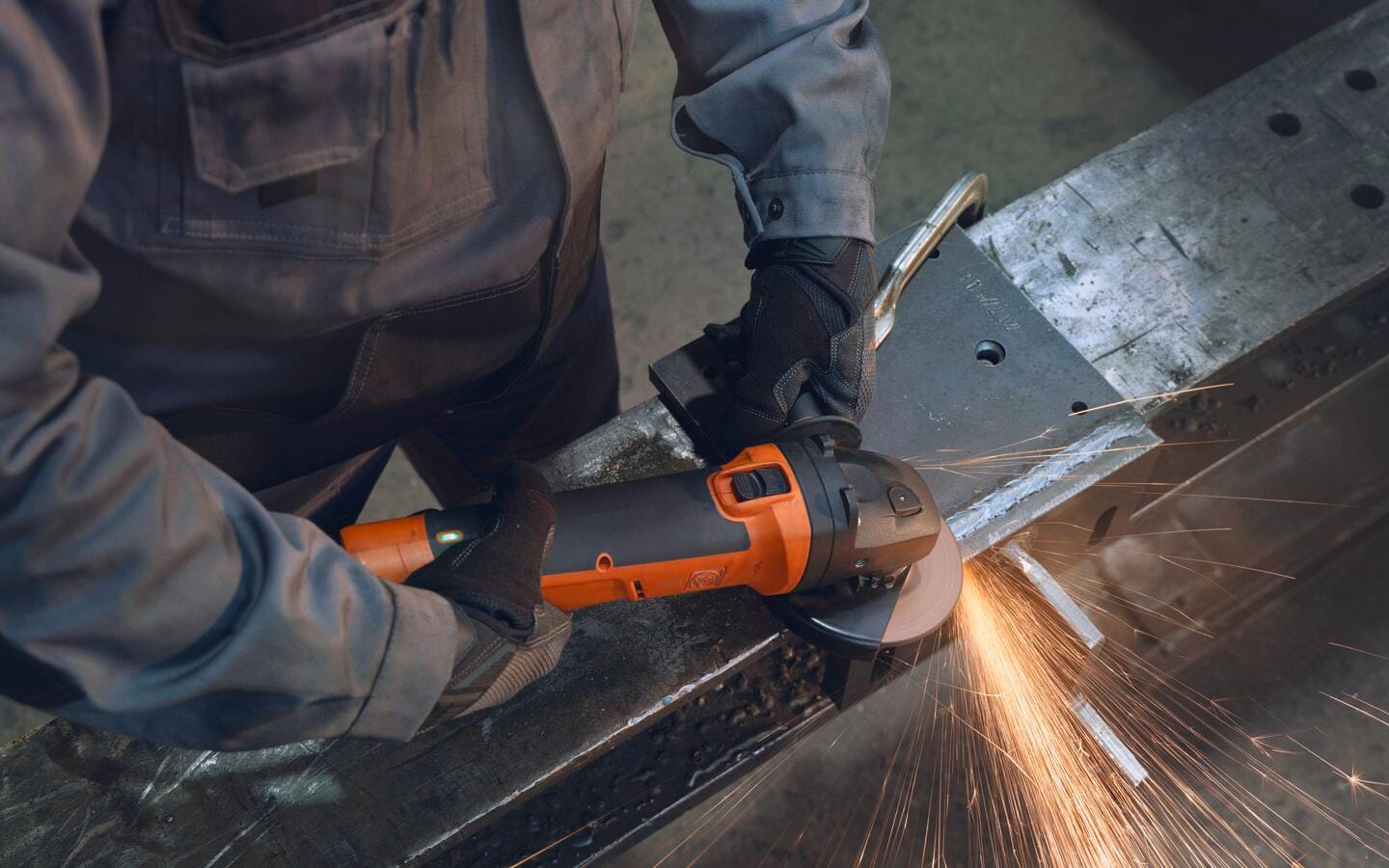 Someone using an angle grinder to weld a metal sheet. 