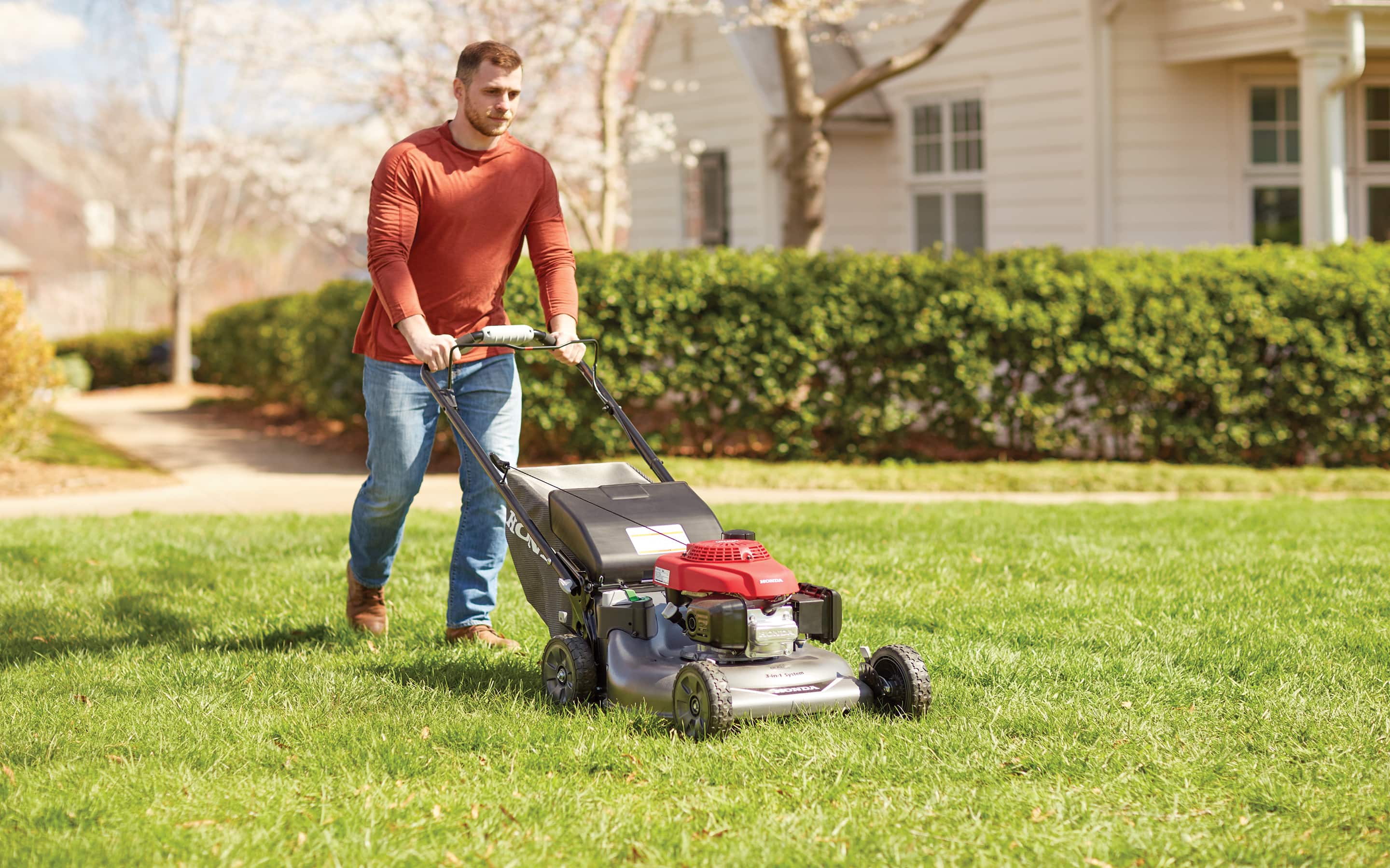 A person mowing a lawn with an electric mower.