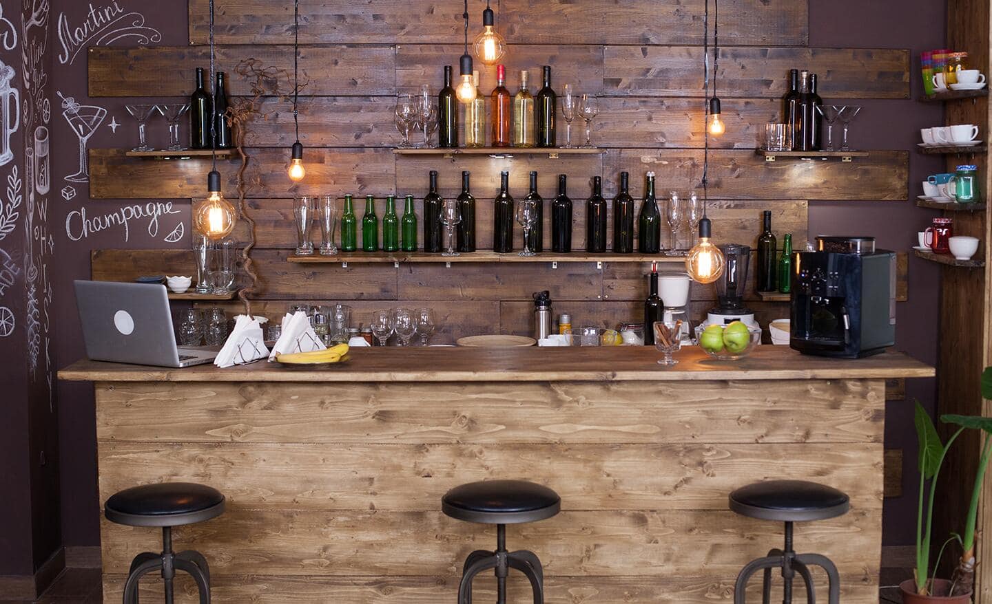A modern home bar featuring wood planks and leather stools.
