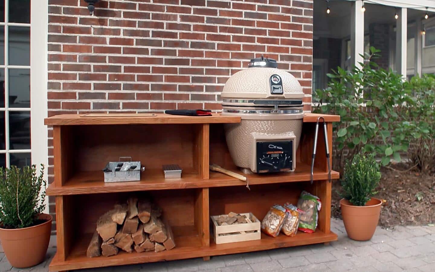 A completed DIY outdoor grill station built in front of a brick wall.