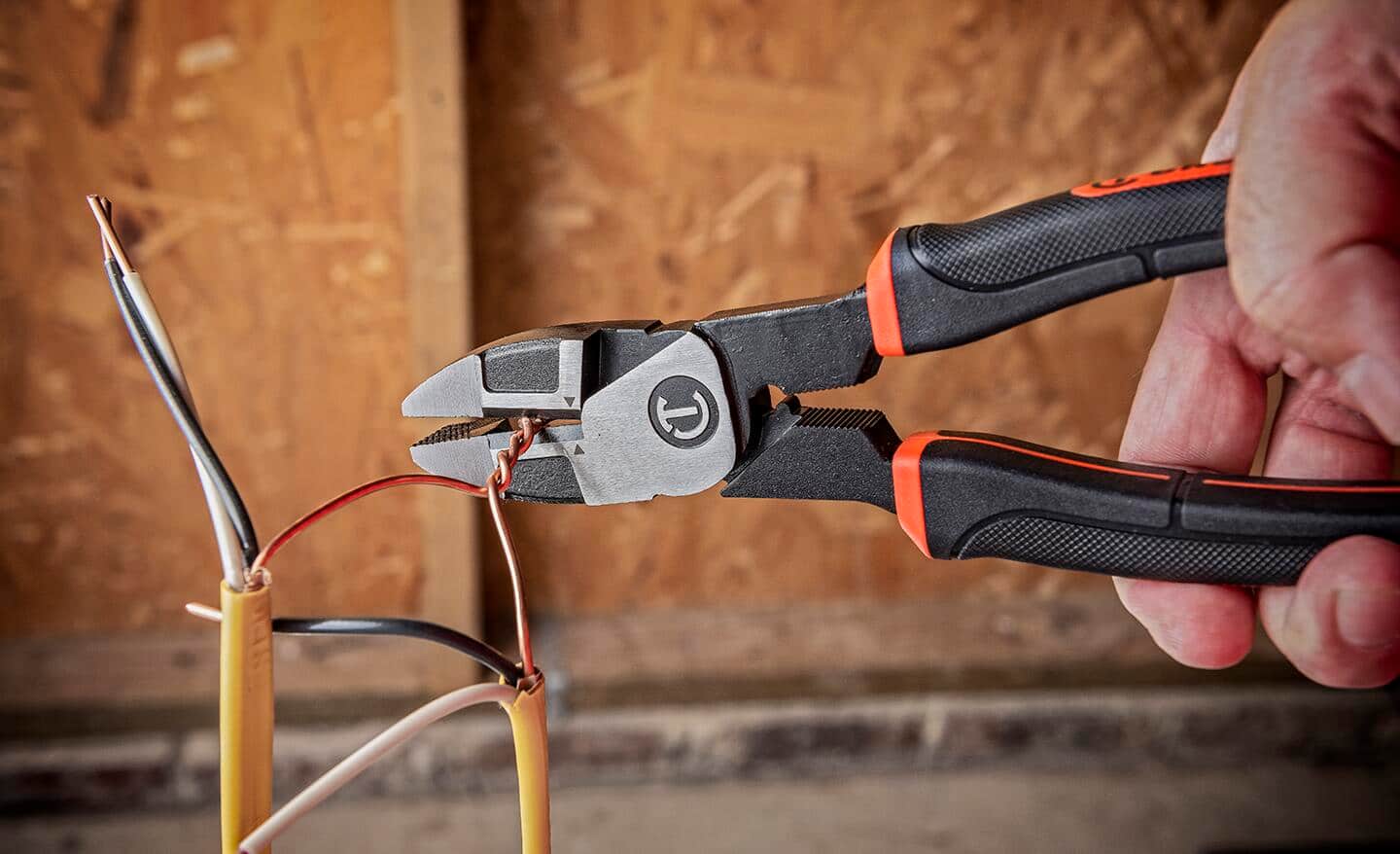A person uses a pair of pliers while wiring an outlet.