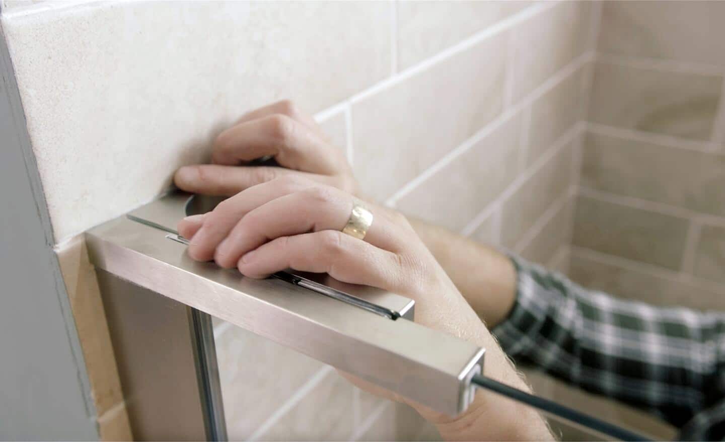 A person installing the L bracket in a pivot shower door.