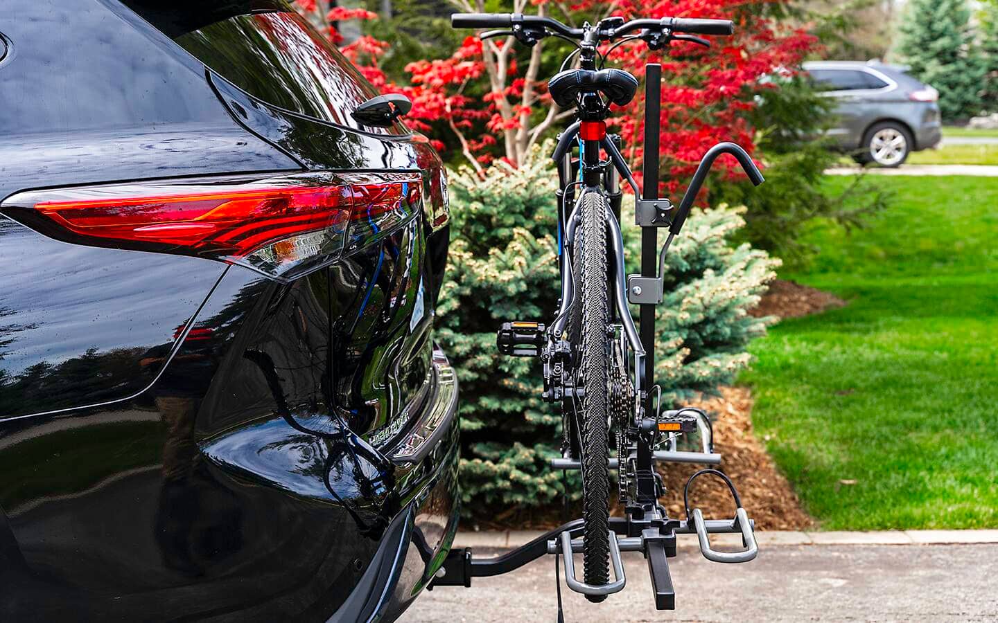 A vehicle features a hitch-mounted bike rack holding a bicycle.